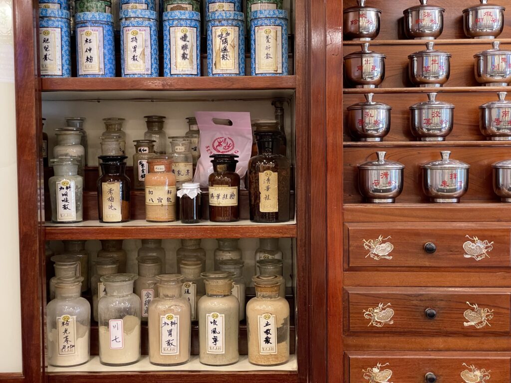 漢方素材の瓶と陶器の生薬壺が並ぶ店内の棚