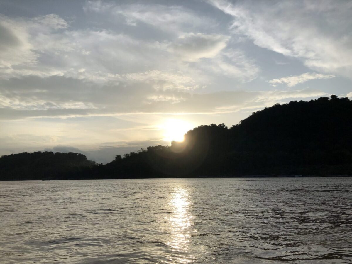 メコン川の対岸の山に沈む夕日と川面の反射